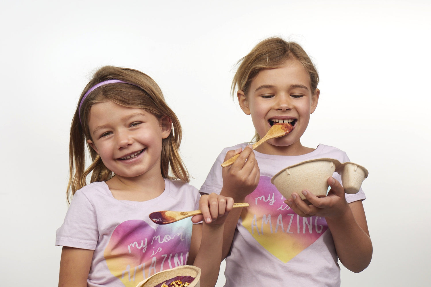 young girls eating frozen fruit bowls with spoons